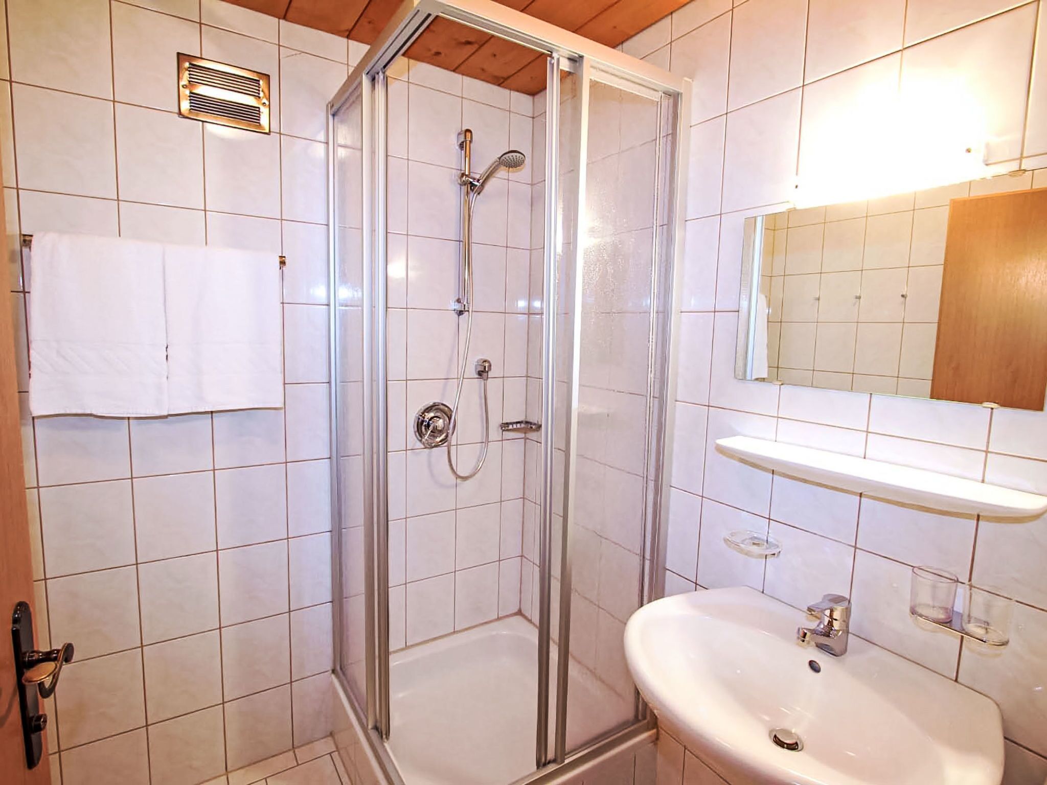 Une salle de bain avec une douche à parois de verre, un lavabo blanc et un miroir au-dessus du lavabo.