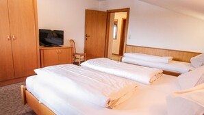 Habitación de hotel con dos camas, un armario de madera, un televisor y una silla.