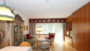 A cozy living room with a sofa, armchair, and a dining table. - Am Birkenhain by Interhome (Seefeld in Tirol)