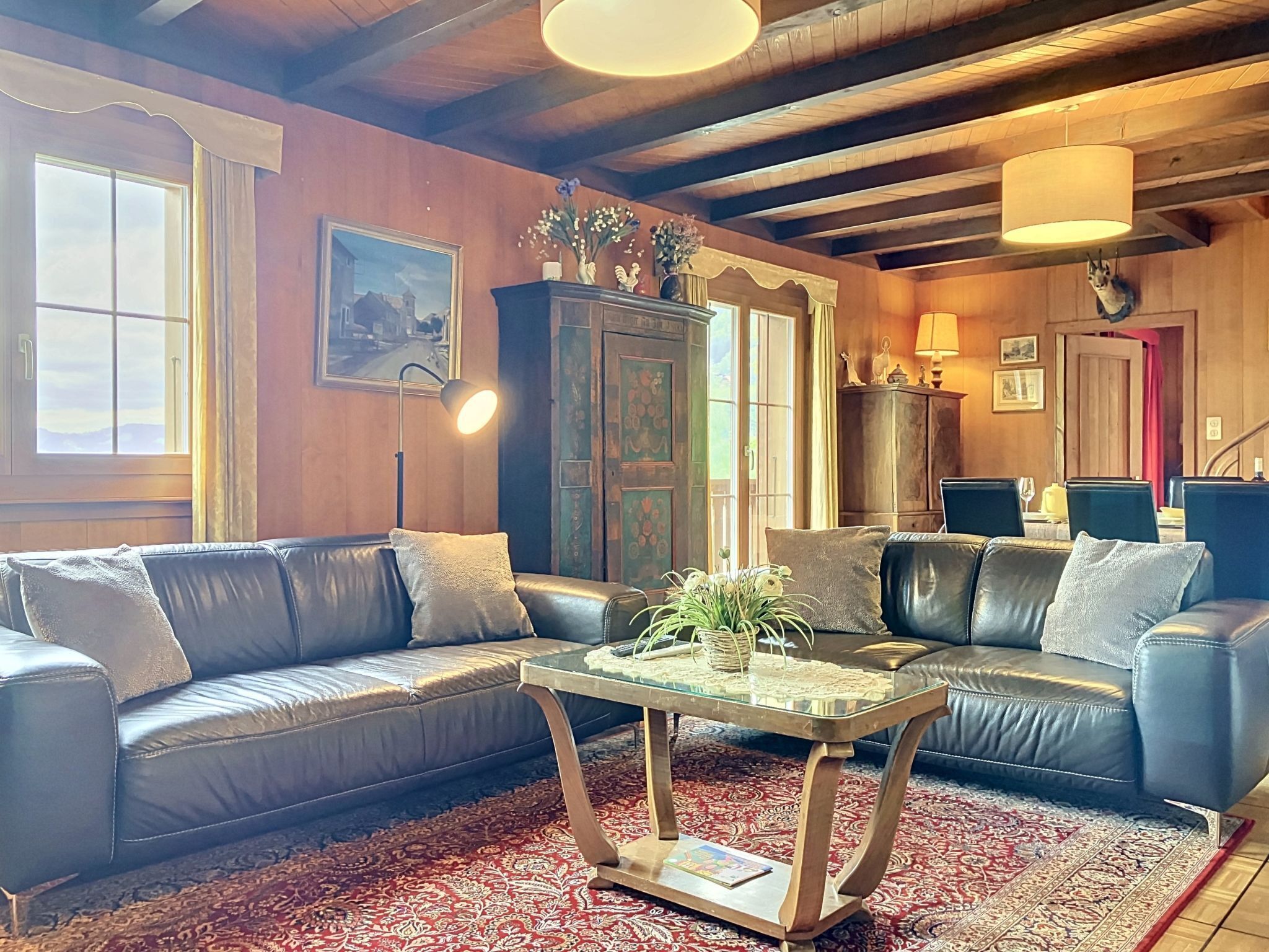 A cozy living room with leather sofas, a glass coffee table, and a patterned rug.