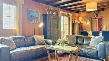 A cozy living room with leather sofas, a glass coffee table, and a patterned rug.