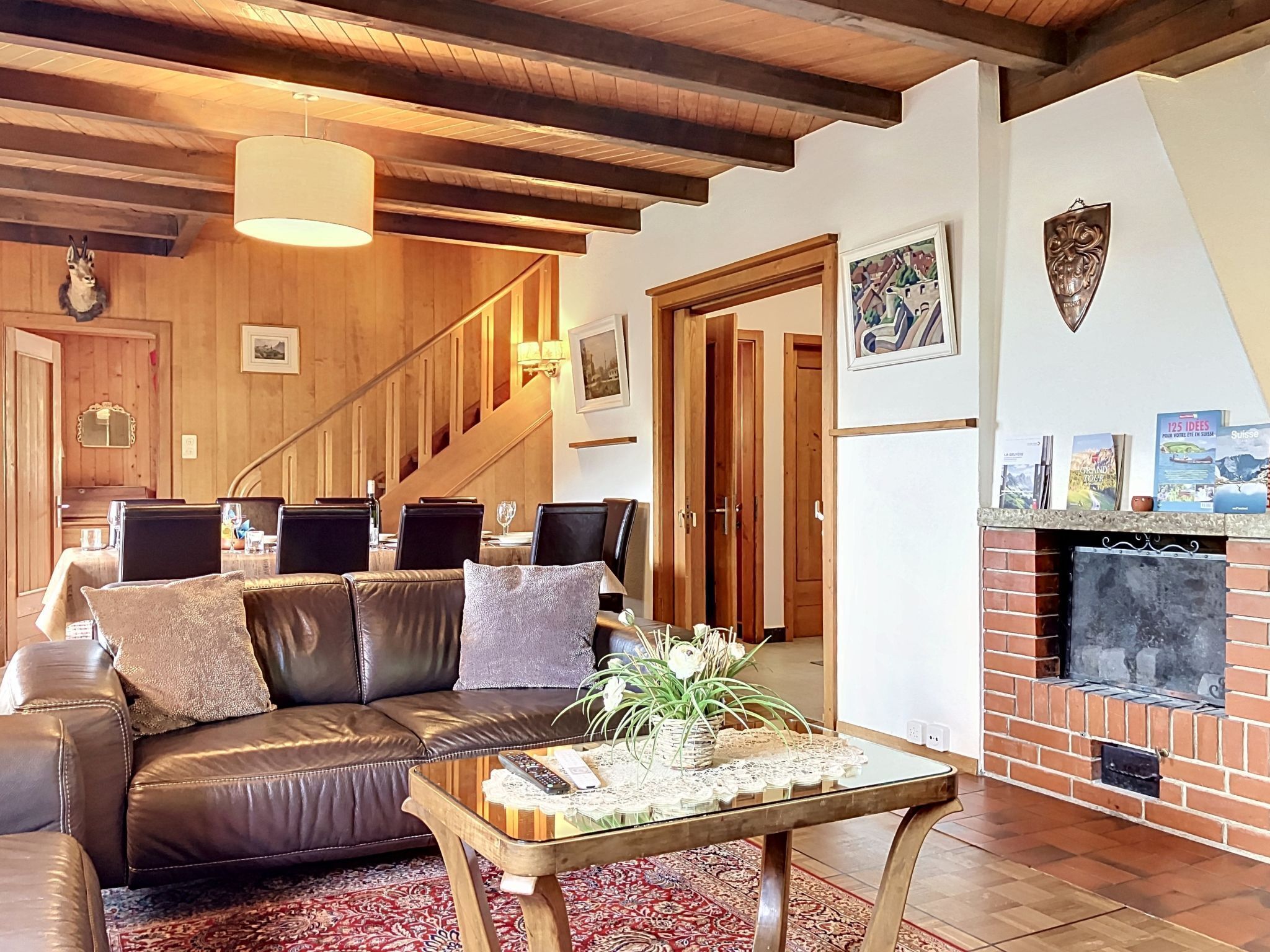 A cozy living room with a leather sofa, a coffee table with decorative items, a fireplace, and a staircase leading to another room.