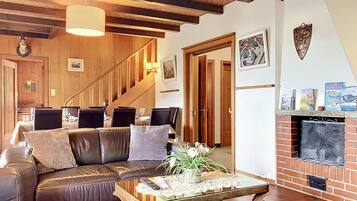 A cozy living room with a leather sofa, a coffee table with decorative items, a fireplace, and a staircase leading to another room.