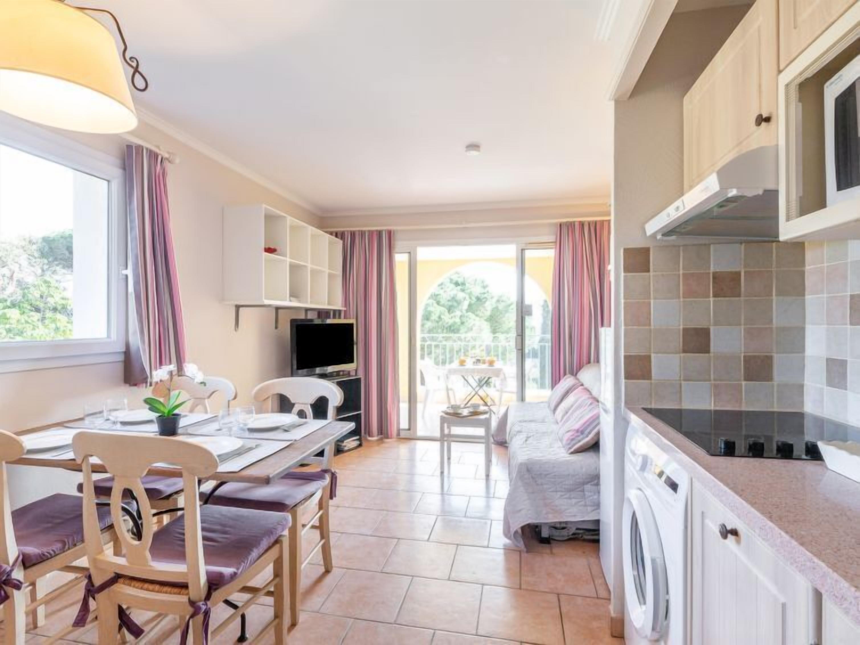 A compact kitchen with a dining area, a washing machine, and a TV.