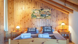Camera da letto con pannelli in legno, un letto, due abat-jour e un quadro appeso al muro.