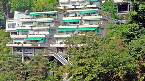 Un quartiere residenziale su una collina con edifici moderni a più piani, caratterizzati da balconi e tende da sole verdi.