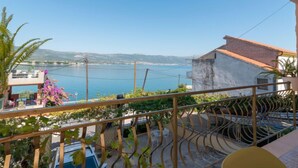 Un balcon avec vue sur la mer et les collines.