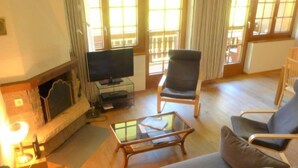 Un salon avec une cheminée, un téléviseur posé sur un meuble et une table basse en verre.