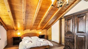 Une chambre à coucher aux murs lambrissés, avec un grand lit, des lampes de chevet et une armoire.