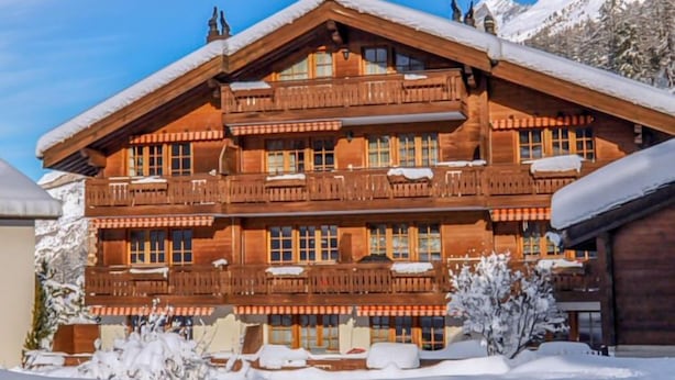 Un chalet en bois à plusieurs étages, doté de balcons et entouré de neige.