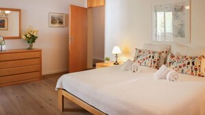 A bedroom with a large bed, wooden dresser, and a door leading to another room. - Attika Wohnung Allod Park Haus C 807 by Interhome (Davos)