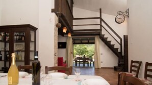 Comedor con una mesa dispuesta para cuatro, una botella de vino y una de agua. Se ve una escalera que conduce a un nivel superior.