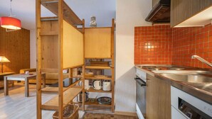 Une cuisine compacte avec des étagères en bois, un crédence carrelé de carreaux rouges et une cuisinière moderne.