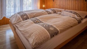 Une pièce aux murs lambrés, avec un lit agrémenté d’une courtepointe matelassée et de coussins.