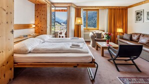 Habitación de hotel con dos camas, un sofá, una silla, una mesa y vistas a las montañas.