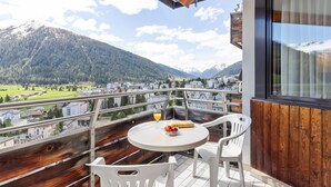 Un balcón con mesa y sillas, con vistas a un paisaje montañoso.