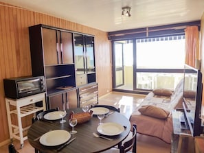 Un comedor con una mesa dispuesta para cuatro, horno empotrado y puerta corrediza de vidrio al exterior.