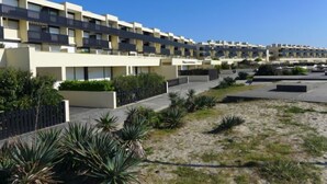 Een modern appartementencomplex met meerdere balkons, een aangelegde tuin en een helderblauwe lucht.