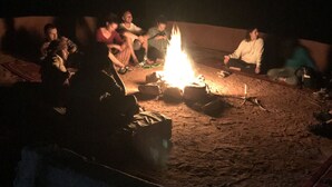 A group of people sitting around a campfire in an outdoor setting. - Bedouin expedition Camp (Wadi Rum)