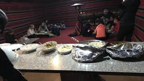 A communal dining area with tables and chairs, a buffet setup with food items, and a red carpeted floor. - Bedouin expedition Camp (Wadi Rum)