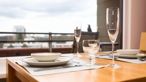 A dining table set with plates, cutlery, and glasses, overlooking a cityscape. - Eifelblick (B906) by Interhome (Lahnstein (Koblenz))