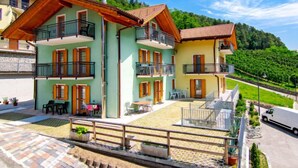 A multi-story building with balconies, outdoor seating, and a paved courtyard. - Al Pescatore by Interhome (Malè)