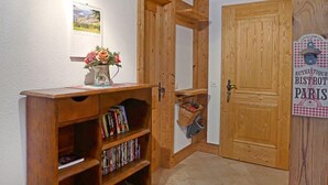 A wooden bookshelf with books and a vase of flowers, a wooden door with a sign, and a small table with a picture on the wall. - Sulegg Apt. I by Interhome (Wengen)