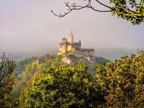 Un château perché sur une colline, entouré de verdure.