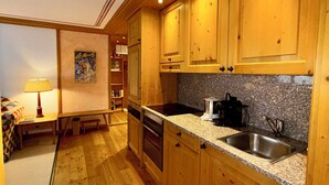 A compact kitchen with wooden cabinets, a granite countertop, a sink, and a coffee maker. - Residenza Chesa Margun 57-4 by Interhome (Silvaplana-Surlej)