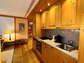 A compact kitchen with wooden cabinets, a granite countertop, a sink, and a coffee maker.