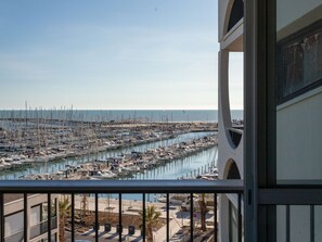 Un puerto deportivo con numerosas embarcaciones amarradas, un cielo despejado y vista al mar.
