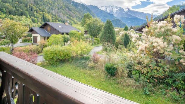 Paisaje montañoso con casas y una terraza de madera.