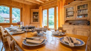 Un comedor de madera con una mesa grande dispuesta para cuatro, rodeado de estanterías y un telescopio.