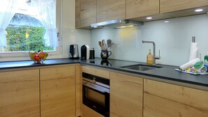 A modern kitchen with wooden cabinets, a stainless steel sink, and a window with a view of greenery. - Salzhubelweg by Interhome (Goldswil)