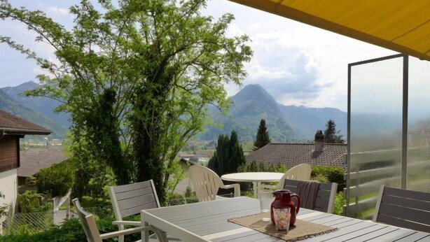An outdoor patio with a table and chairs, overlooking a mountainous landscape. - Salzhubelweg by Interhome (Goldswil)