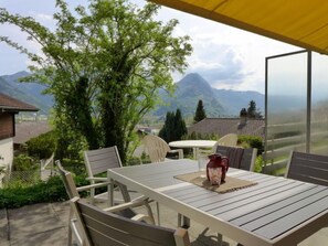 Une terrasse extérieure avec une table et des chaises, offrant une vue sur un paysage montagneux.