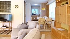 A living room with a sofa, TV, and a dining area with chairs and a table. - Salzhubelweg by Interhome (Goldswil)