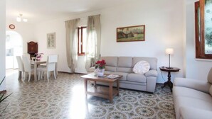 A living room with a sofa, coffee table, and dining area with chairs and a table. - Vacation home Sandra by Interhome (Forte dei Marmi)