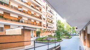 Un edificio residencial de varios pisos con balcones, un patio central con plantas y una escalera que conduce a los pisos superiores.