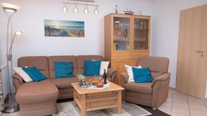 Un salon avec un ensemble de canapés marron, un meuble en bois et un lampadaire.