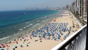 A beach with numerous umbrellas and people, a clear sky, and tall buildings in the background. - Torre Principado by Interhome (Benidorm)
