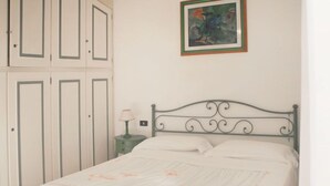 Un dormitorio con cama, mesita de noche, lámpara y armario.