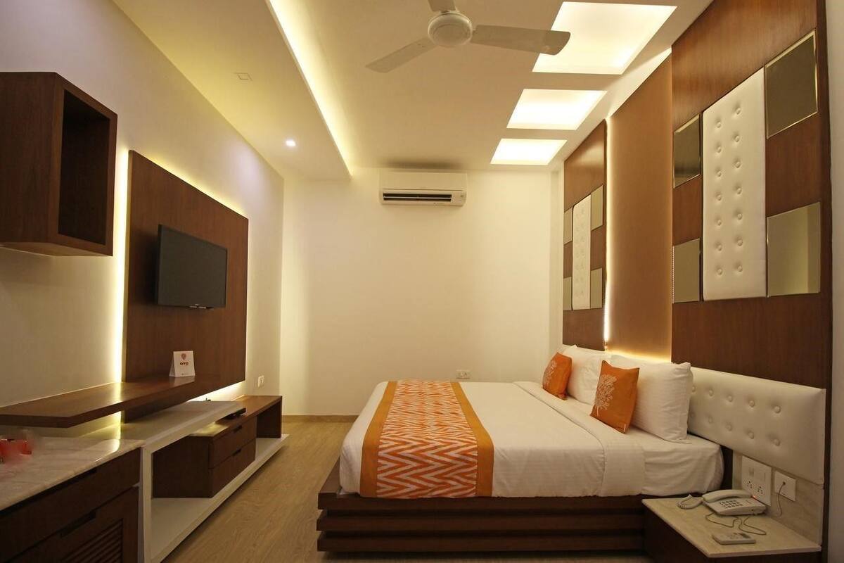 Een hotelkamer met een bed, nachtkastje, televisie en inbouwkasten.