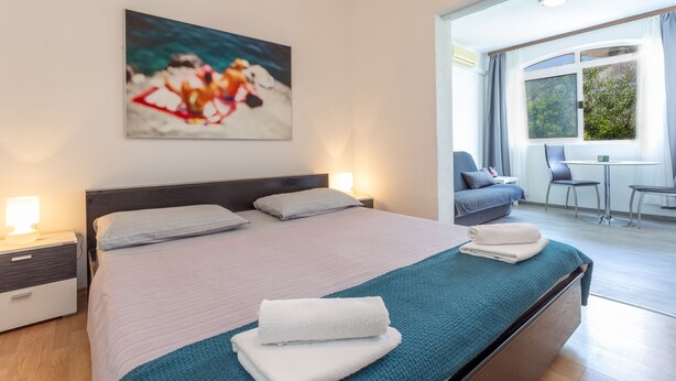 A modern hotel room with a large bed, a desk, and a view of the outdoors. - Apartments Milka (Hvar)