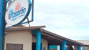 Un bâtiment sur lequel on peut lire l’inscription « Pousada Casarão Domar », et une zone extérieure abritée avec des bancs.