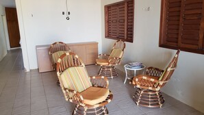 Une pièce avec des chaises en osier, une petite table et un buffet.