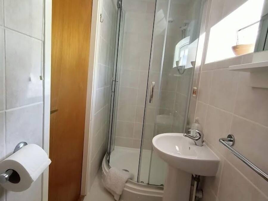 Ein Badezimmer mit Glasdusche, Waschbecken und Toilettenpapierhalter.