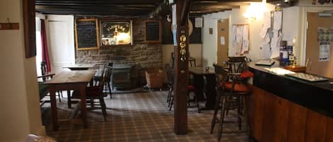 Un pub con piso a cuadros, mesas de madera y una zona de bar.