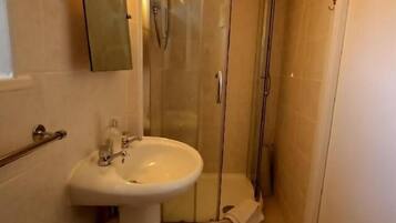 Un baño con cabina de ducha de vidrio, un lavamanos y un espejo.