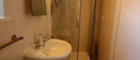 Un bagno con box doccia in vetro, lavabo e specchio.